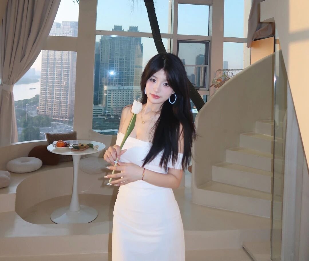 学员照片，女生身着白色裙于室内，背景为城市景观